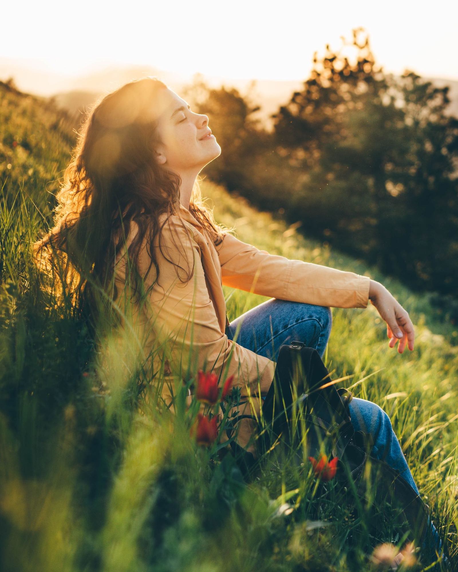 Woman sitting in grassy meadow during golden hour