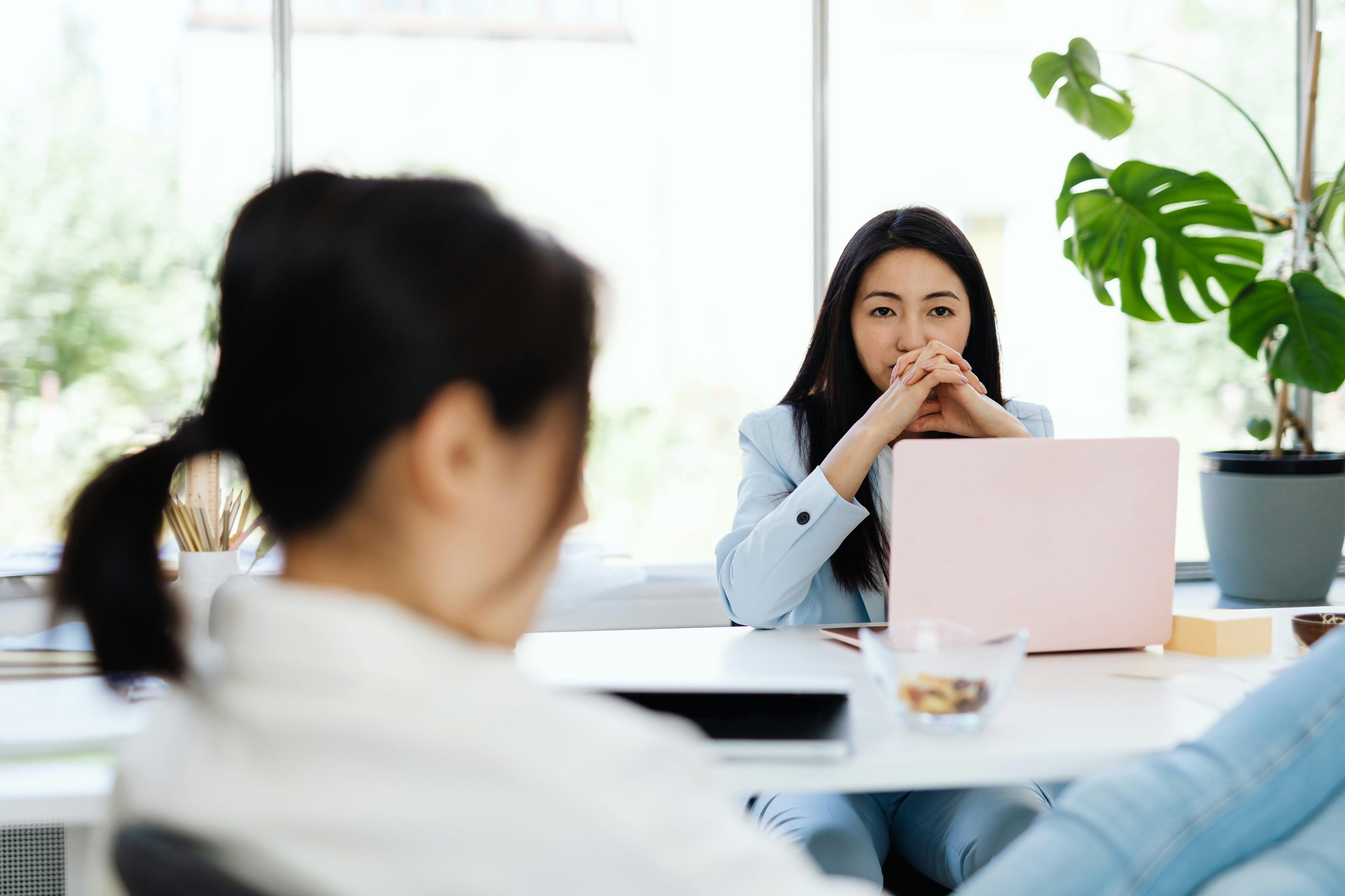Two women in an office setting, one of them in thought