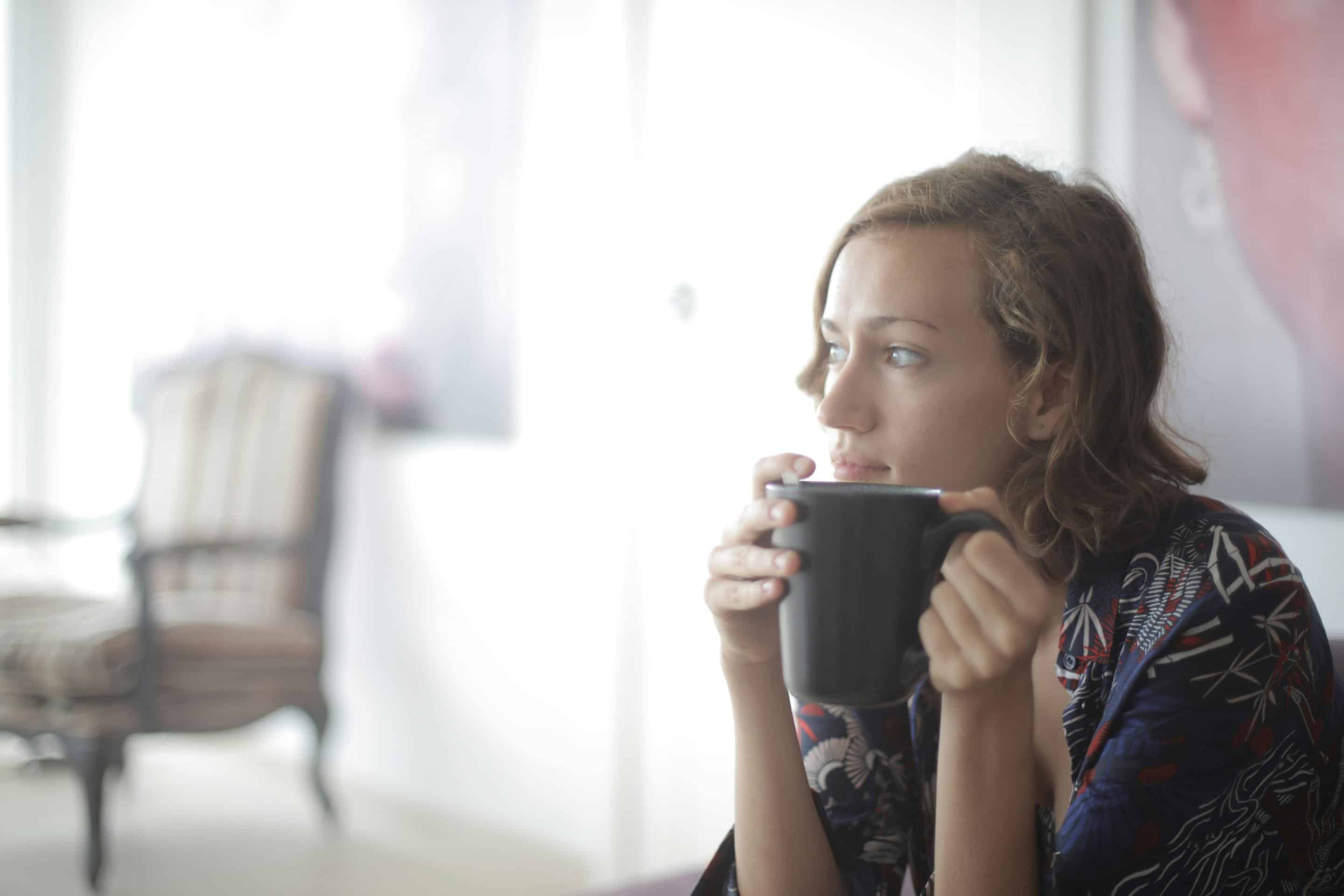 Woman sitting with coffee appearing to be in thought